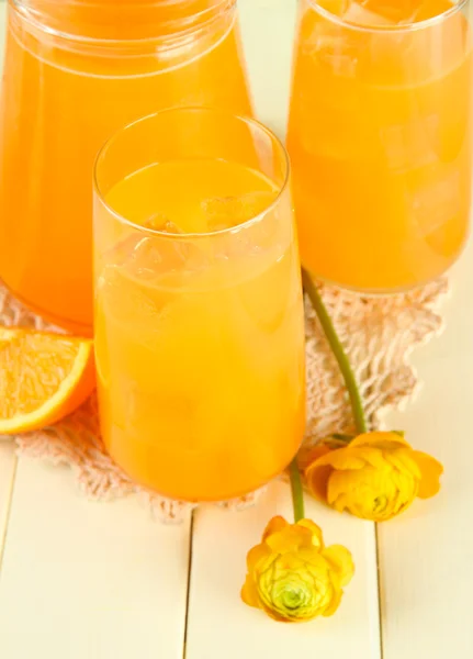 Glazen en werper sinaasappelsap op witte houten achtergrond — Stockfoto