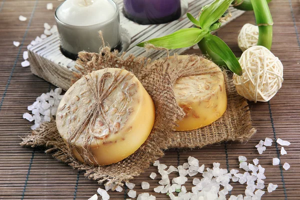 Hand-made soap and sea salt on grey bamboo mat — Stock Photo, Image