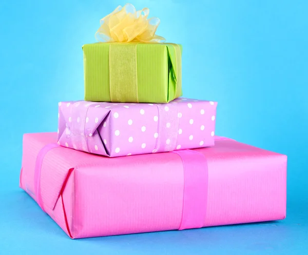Yay üzerinde mavi arka plan ile parlak hediyeler — Stok fotoğraf
