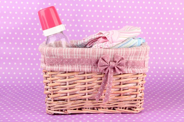 Hermosa cesta de ropa de bebé sobre un fondo rosa —  Fotos de Stock
