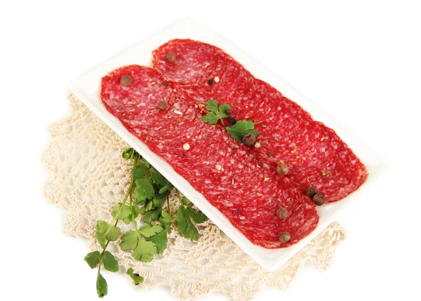 Tasty salami on plate on napkin isolated on white — Stock Photo, Image