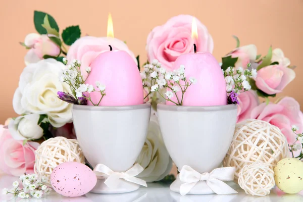 Easter candles with flowers on beige background — Stock Photo, Image