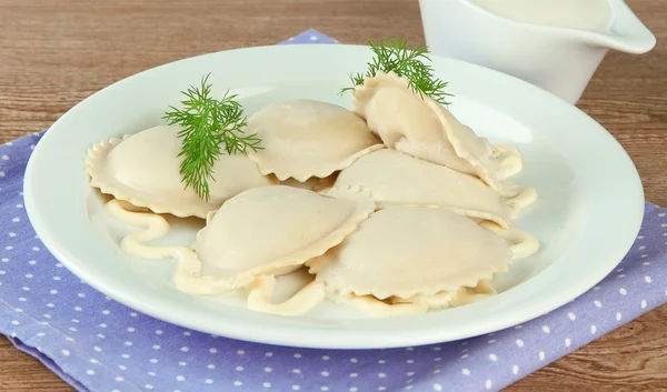 Tasty dumplings on plate, on wooden table — Zdjęcie stockowe