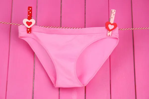 Womans panties hanging on a clothesline, on pink wooden background — Stock Photo, Image