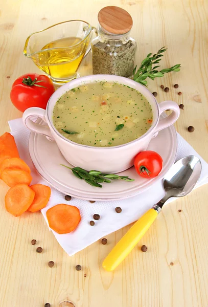 Питательный суп в розовой сковороде с ингредиентами на деревянном столе крупным планом — стоковое фото