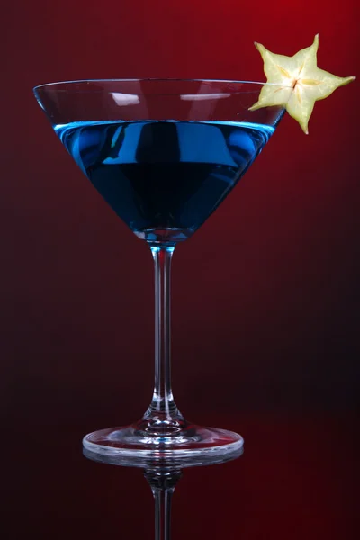Голубой коктейль в бокале мартини на темно-красном фоне — стоковое фото
