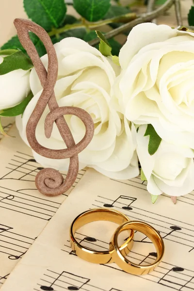 Fenda aguda, rosas e anéis de casamento no fundo musical — Fotografia de Stock