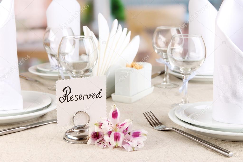 Reserved sign on restaurant table with empty dishes and glasses