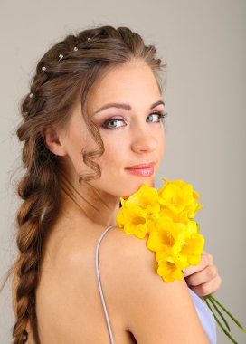 güzel saç modeli ve gri arka plan üzerinde çiçekler olan kadın