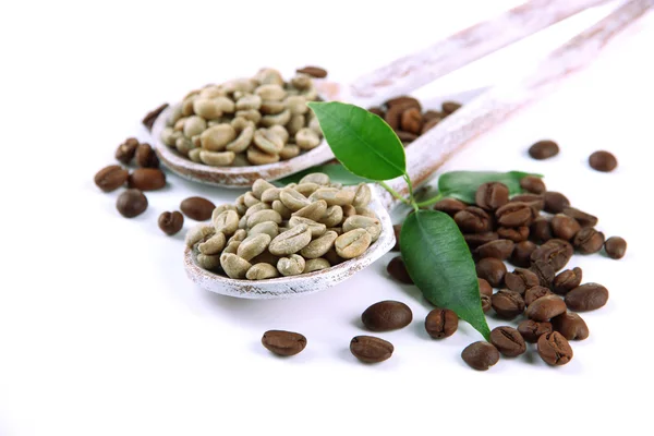 Grãos de café verde e marrom em colheres de madeira e folhas isoladas em branco — Fotografia de Stock