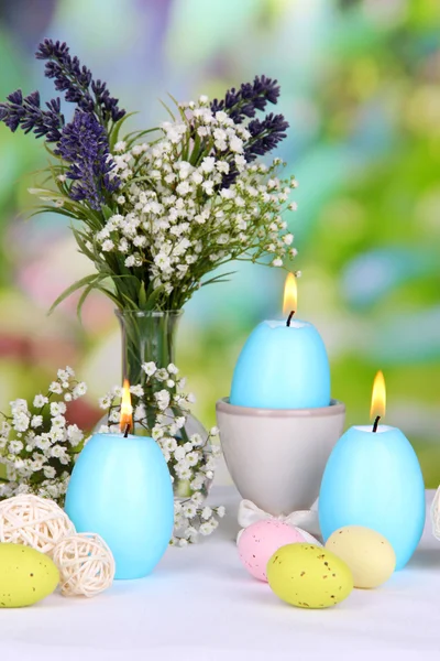 Pasen kaarsen met bloemen op lichte achtergrond — Stockfoto