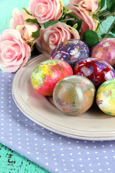 Huevos de Pascua en plato con servilleta y flores de cerca — Foto de Stock