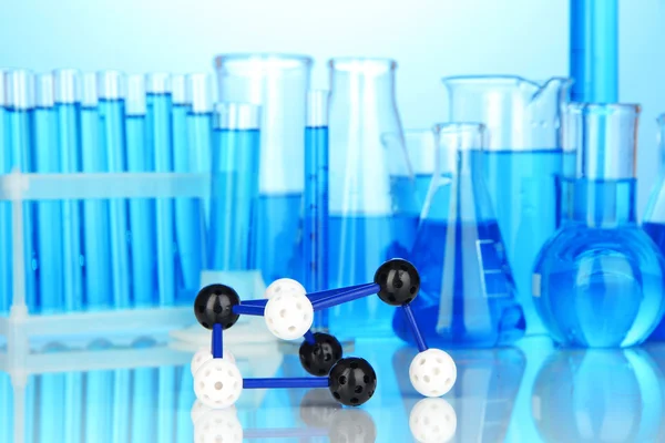 Molecule model and test tubes with liquid on blue background — Stock Photo, Image