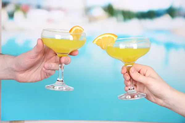 Cocktails i mäns och kvinnors händer på pool bakgrund — Stockfoto