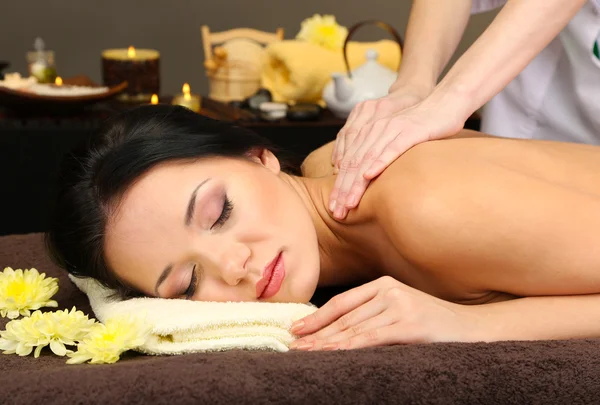 Vacker ung kvinna i spasalong får massage, på mörk bakgrund — Stockfoto