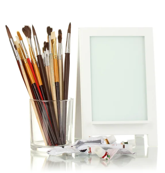 Photo frame as easel with artist's tools isolated on white — Stock Photo, Image