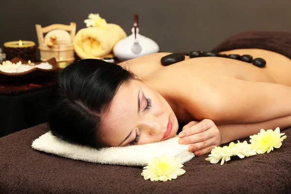 Krásná mladá žena ve spa salonu wellness kameny, na tmavém pozadí — Stock fotografie