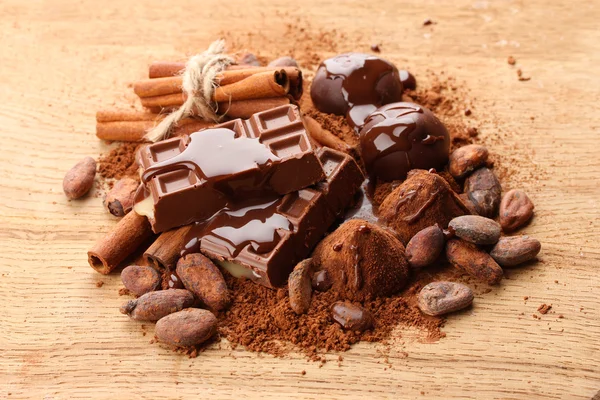 Samenstelling van chocolade snoepjes, cacao en specerijen op houten achtergrond — Stockfoto