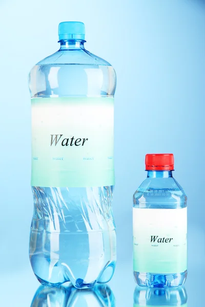 Různé lahve s vodou s popiskem na modrém pozadí — Stock fotografie