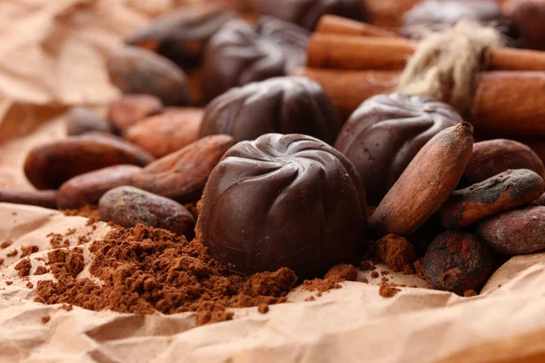Samenstelling van chocolade snoepjes, cacao en specerijen op bruine achtergrond — Stockfoto