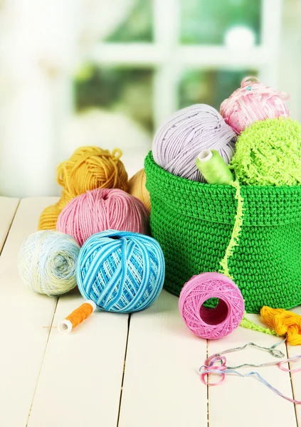 Fil coloré pour tricoter en panier vert sur table en bois sur fond de fenêtre — Photo