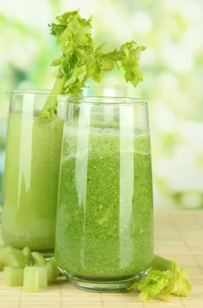 Briller av grønn selleri-juice på bambusmatte, med grønn bakgrunn – stockfoto