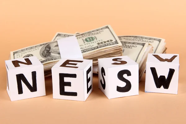 White paper cubes labeled "News" with money on beige background — Stock Photo, Image