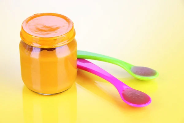 Baby food with weaning spoons on yellow background — Stock Photo, Image