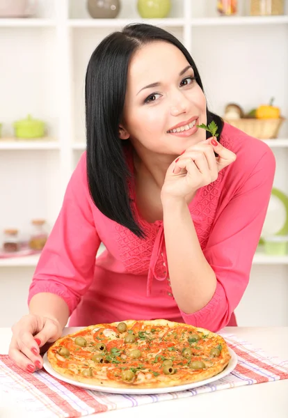 Piękna dziewczyna z pyszną pizzę na tle kuchnia — Zdjęcie stockowe