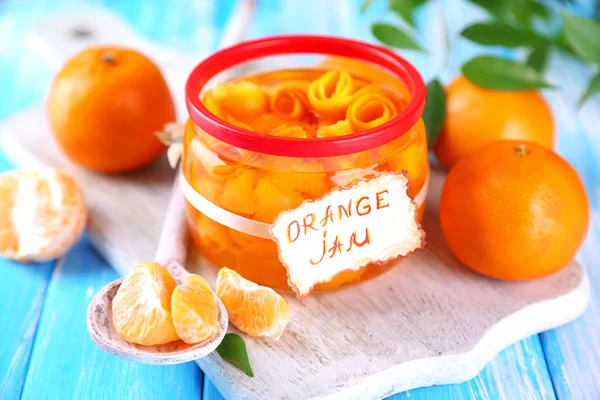 Oranžový jam s kůrou a mandarinky, na modré dřevěný stůl — Stock fotografie