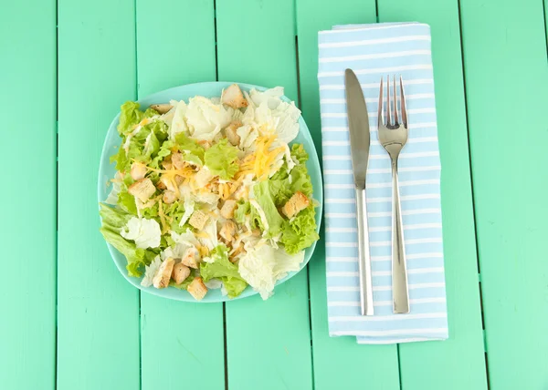 Caesar-Salat auf blauem Teller, auf farbigem Holzhintergrund — Stockfoto