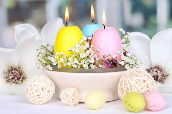 Easter candles with flowers on window background — Stock Photo, Image