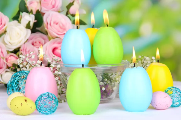 Velas de Pascua con flores sobre fondo brillante —  Fotos de Stock