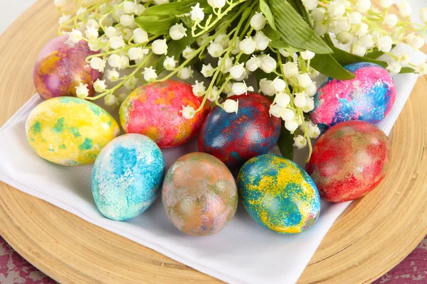 Easter eggs on wooden plate on napkin with flowers close-up — Stock Photo, Image