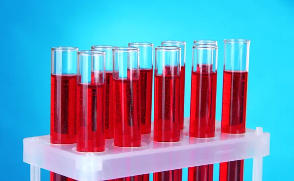 Тестові трубки з кров'ю в лабораторії на синьому фоні — стокове фото