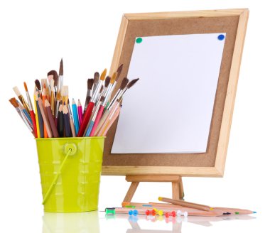 Small easel with sheet of paper with art supplies isolated on white clipart