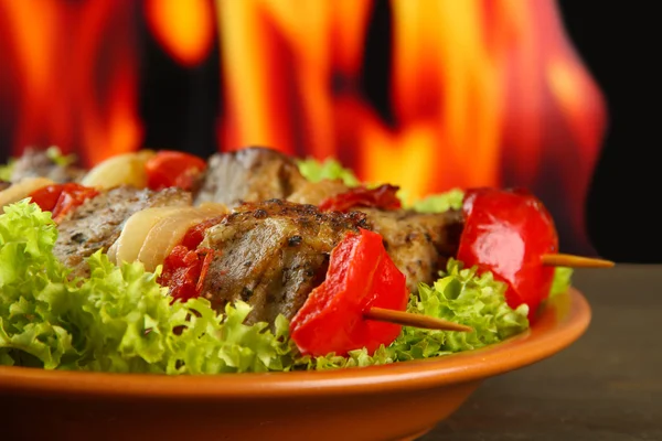 Viande et légumes grillés savoureux dans une assiette, sur fond de feu — Photo