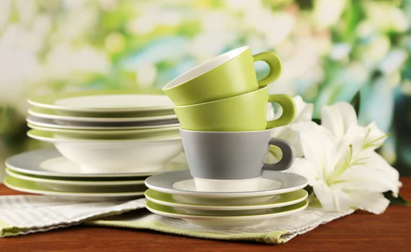 空盘子和杯子绿色背景上的木桌上 — 图库照片