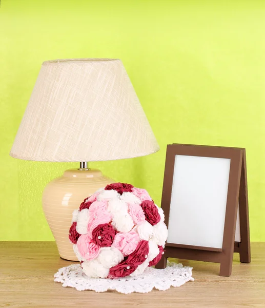 Marco de fotos marrón y lámpara sobre mesa de madera sobre fondo de pared verde — Foto de Stock