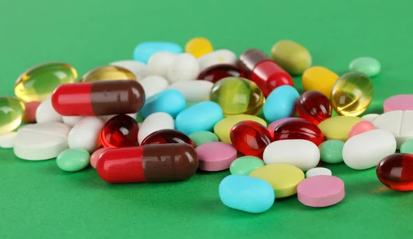 Assortment of pills, tablets and capsules on green background — Stock Photo, Image