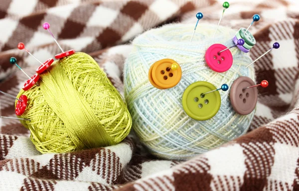 Buttons of different colors, and the two tangle thread on checked plaid — Stock Photo, Image