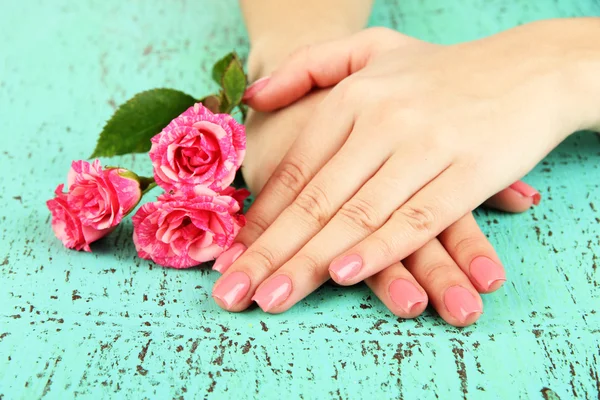 Kadın pembe manikür ve çiçekler, renk arka plan üzerinde elleriyle — Stok fotoğraf