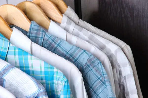 Men's shirts on hangers on wooden background — Stock Photo, Image