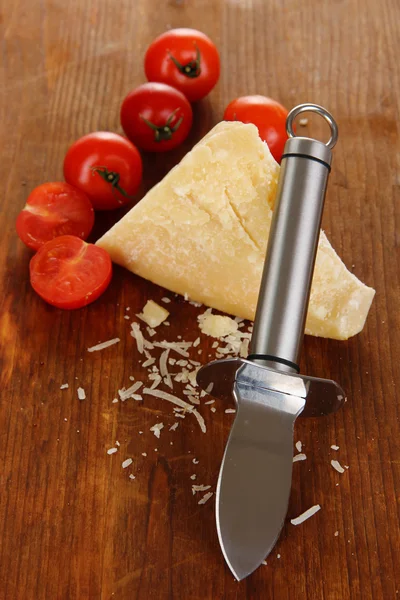 Piece of Parmesan cheese with knife on wooden table close-up — Stock Photo, Image