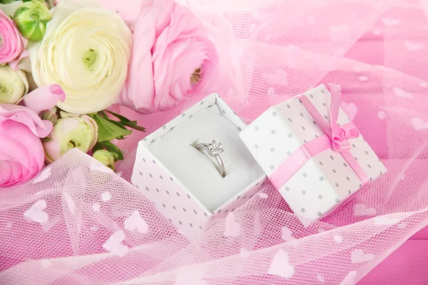 Ranunculus (persian buttercups) and engagement ring, on pink cloth — Stock Photo, Image