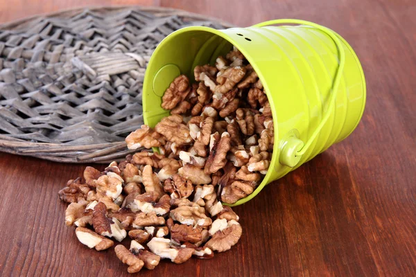 Overturned bucket with nuts on wooden background — Stock Photo, Image