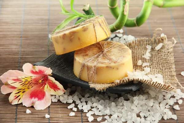 Handgemaakte zeep en zeezout op grijs bamboe mat — Stockfoto