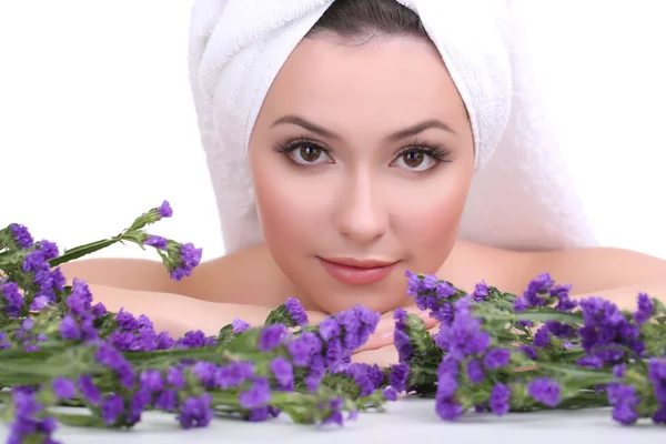 Belle jeune femme avec serviette sur la tête et fleurs isolées sur blanc — Photo