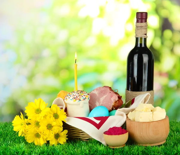 Cesta de Pascua: Foto conceptual de la comida tradicional de Pascua en canasta de mimbre, sobre hierba verde, sobre fondo brillante —  Fotos de Stock