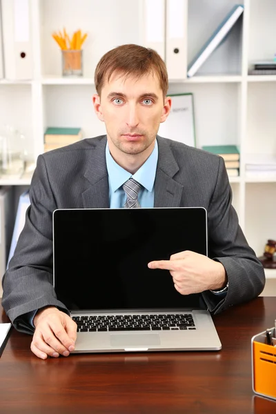 Młody biznesmen z komputera laptop stoi na swoim miejscu pracy — Zdjęcie stockowe